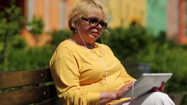 Frau in gelber Jacke mit Tablet-Computer. Frau hält Pad mit Headset — Stockvideo