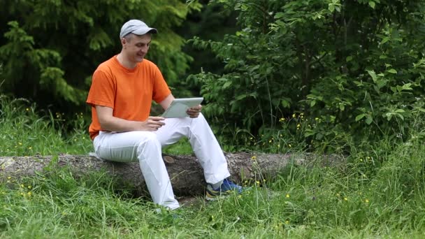 Человек с планшетным компьютером в лесу — стоковое видео