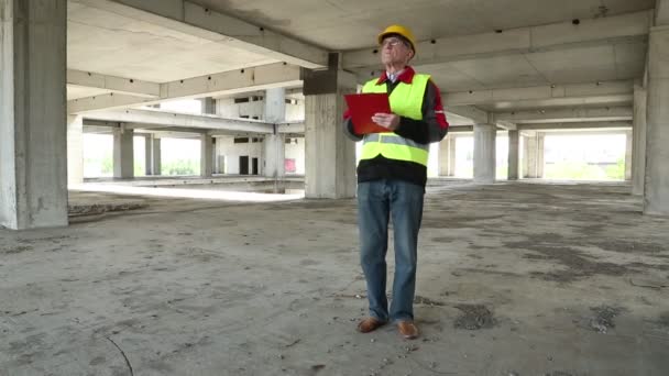 Ingenieur in de gele helm blijft op bouwplaats — Stockvideo