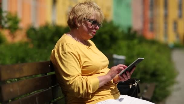 La mujer de chaqueta amarilla usa libro electrónico. La mujer sostiene el libro electrónico — Vídeo de stock