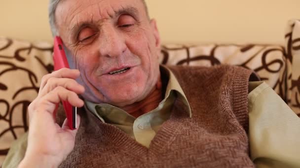 Homem sênior com smartphone vermelho fala — Vídeo de Stock