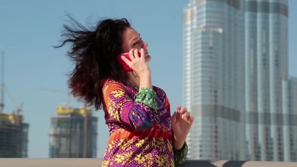 Mujer se para cerca de rascacielos y se comunica a través de teléfono inteligente — Vídeo de stock