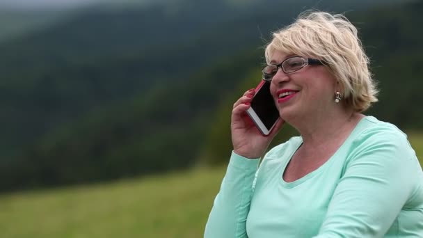 Kvinnan talar i en mobiltelefon på natur — Stockvideo