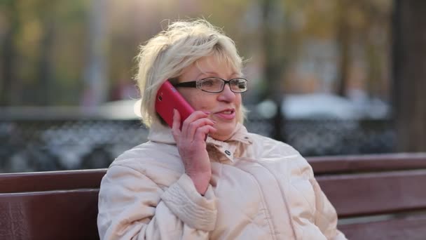 Vrouw zit op de Bank en praat op de rode smartphone — Stockvideo