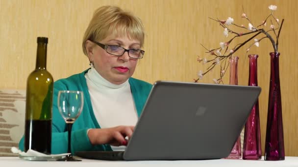 Vrouw giet en drinkt rode wijn en typen tekst op laptop — Stockvideo