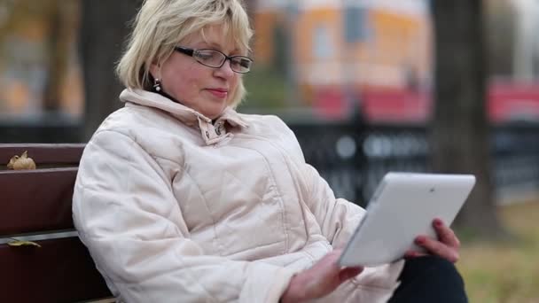 Žena sedí na lavičce a použití tabletového počítače. Žena s Tablet Pc — Stock video