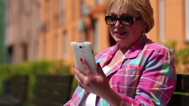 Vrouw op de bank zit en communiceert via smartphone — Stockvideo