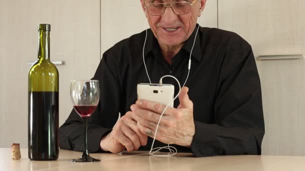 Un homme avec un téléphone portable s'assoit à table et boit du vin — Video