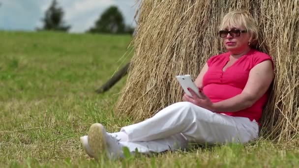 Femme avec smartphone assis près de la botte de foin — Video