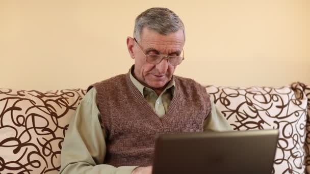 Senior man types text using laptop — Stock Video