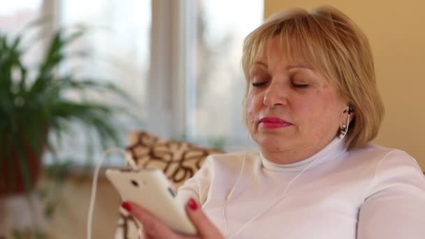 Donna con smartphone si siede e ascolta la musica — Video Stock