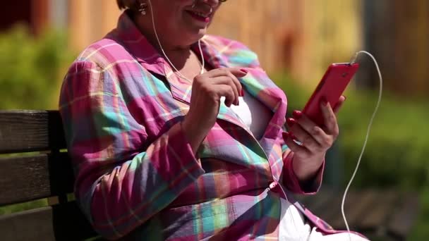 Femme assise sur le banc et communique via smartphone — Video