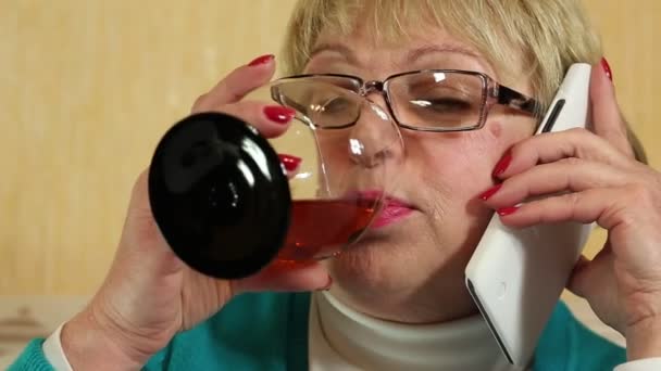 Femme avec téléphone cellulaire blanc parle, boit du brandy et rit — Video