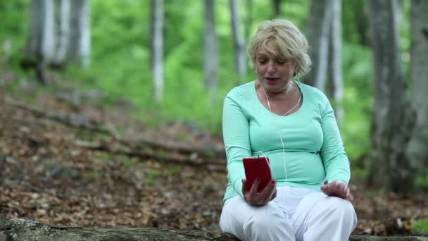 Kadın düşmüş bir ağaç üzerinde oturur, smartphone iletişim kurar — Stok video