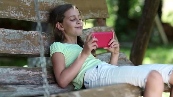 Girl with red smartphone sits and listens to music — Stock Video