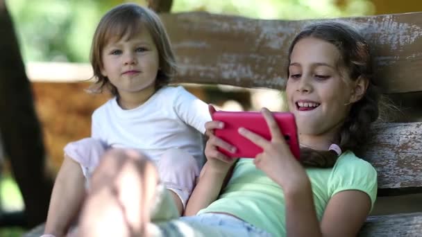 Twee kleine meisjes met rode smartphone — Stockvideo