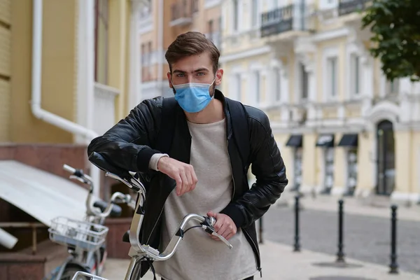 Bicycle man in medical protective mask and backpack. Covid concept health and safety, coronavirus quarantine, next wave covid virus protection