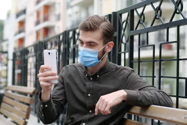 Νεαρός Άνδρας Μπλε Ιατρική Προστατευτική Μάσκα Κάθεται Στον Πάγκο Και — Φωτογραφία Αρχείου