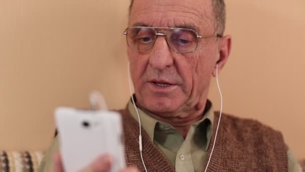 Senior man with white smartphone speaks — Stock Video