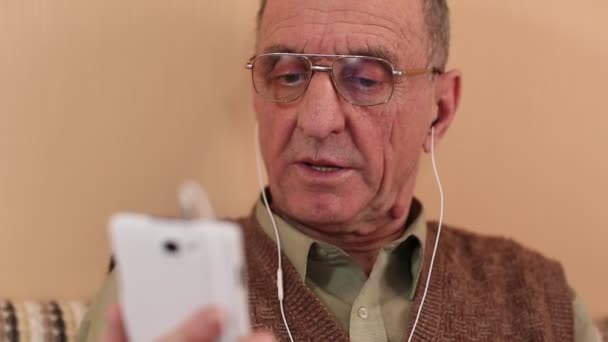 Senior man met witte smartphone spreekt — Stockvideo