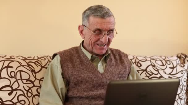 Hombre mayor se comunica a través de ordenador portátil — Vídeos de Stock