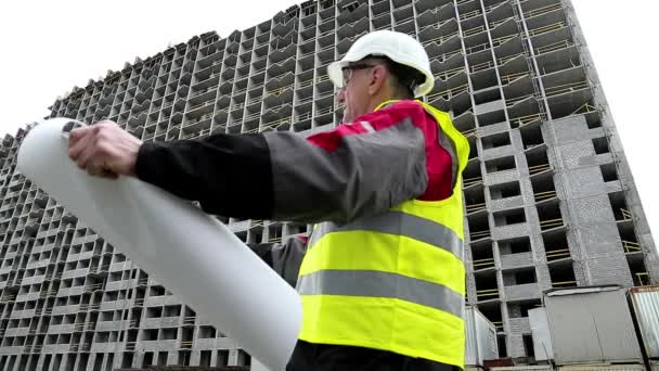 Baumeister mit Konstruktionszeichnungen auf der Baustelle — Stockvideo