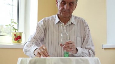 Adam masada oturur ve votka içer.