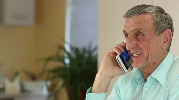 Hombre con teléfono inteligente blanco habla y sonríe — Vídeos de Stock