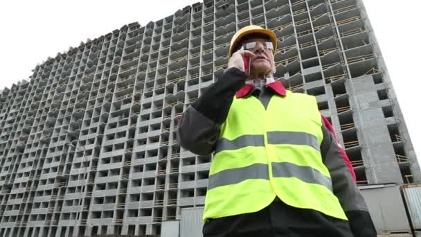 Master builder in hard hat with smartphone — Stock Video