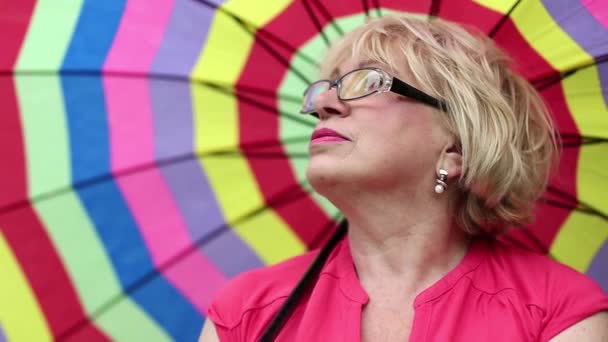 Femme âgée dans des lunettes avec parapluie coloré — Video