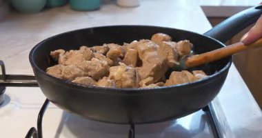 Kızarmış et. Aşçı et parçalarını fırında kızartılmış tavada soğanla karıştırır