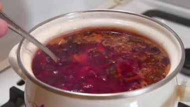 Ukrayna çorbası fırında pişirilir. Aşçı çorbayı kaşıkla karıştırır. Ukrayna 'nın ulusal yemeği. Ukrayna mutfağının ana yemeği. İlk yemekler. Kırmızı Ukrayna borsch 'u tencerede kaynıyor.