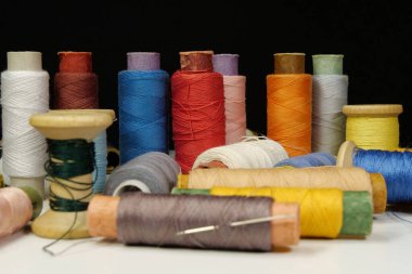 Multicolored spools thread. Spools of multi-colored threads lies on white table on black background, close-up shot photo