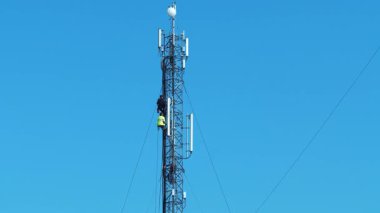 KYIV, UKRAINE, 29 Mart 2025: 3 işçi baz istasyonunda. Tamirciler yeni kablo ve ekipman kuruyor. İşçiler baz istasyonunu onarıyor. Mavi arka plandaki baz istasyonu. İşçiler, işte bakım personeli.