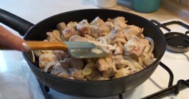 Kızarmış et. Aşçı, et parçalarını soğanla karıştırıp, gaz sobasında kızartma tavasına koyar.