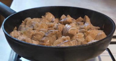 Kızarmış et. Soğanlı et parçaları, gaz ocağında tavada kızartılıyor. Kızartma tavası buharlaşıyor.