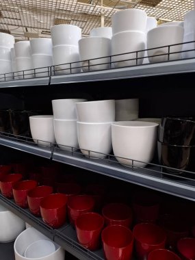 Süpermarket raflarında beyaz, siyah ve kırmızı seramik saksılar. Çiçekçide seramik ürünler