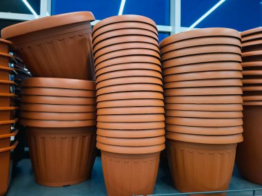 Plastik saksılar bir çiçekçide satılır. Raflardaki büyük saksılar
