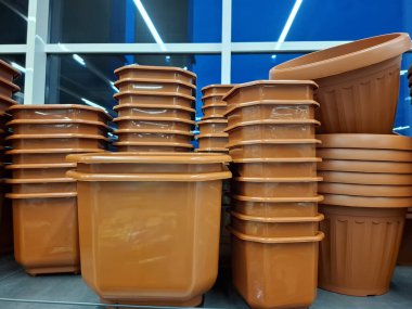 Plastik saksılar bir çiçekçide satılır. Süpermarket raflarında büyük kahverengi saksılar