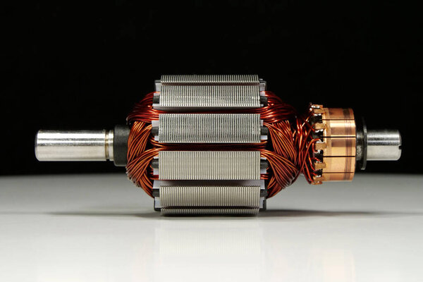 На столе лежит ротор электродвигателя с медной катушкой от ударного массажера