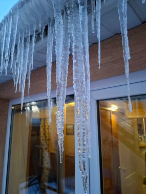 Soğuk kış, buz oluşumu. Evin çatısında uzun buz sarkıtları asılı.