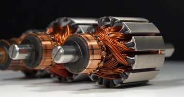 İki perküsyon masaj aleti ve mutfak blendırı gibi küçük ev aletlerinden bakır bobinli elektrikli motorların pervaneleri veya armatürleri. Üç pervane beyaz masada yatıyor.