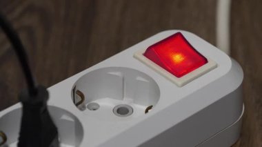 Kırmızı enerjili, göstergeli ve yerleştirilmiş prizli elektrikli portatif soket yerde duruyor.