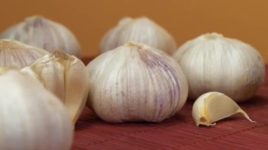 Sarımsak sarı arka planda döner. Sarımsak, Allium sativum, Allium cinsindeki soğan çiçekli bitkiler. Sarımsak - sağlık için yararlı özelliklere sahip çok sağlıklı bir ürün