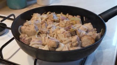 Aşçı sobada soğanlı et parçaları karıştırır. Kızarmış et.