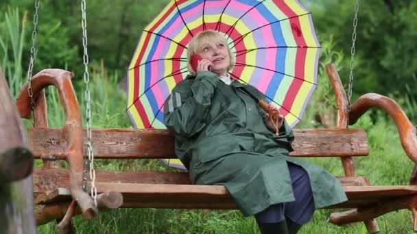 Woman with umbrella communicates via cell phone — Stock Video