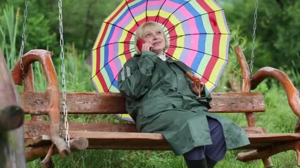 Frau mit Regenschirm kommuniziert per Handy — Stockvideo