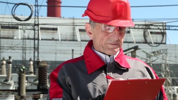 Engenheiro construtor em capacete vermelho escreve — Vídeo de Stock