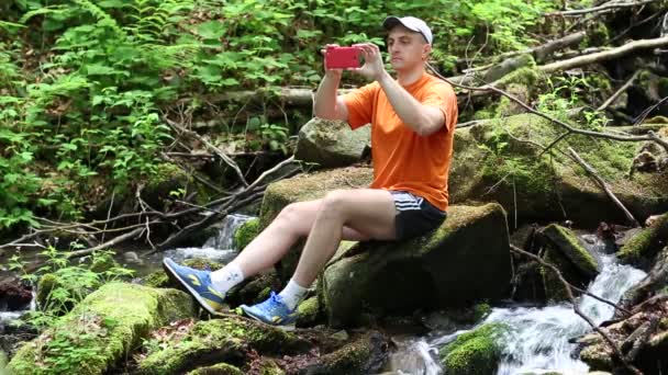 Mann sitzt auf großem Stein — Stockvideo