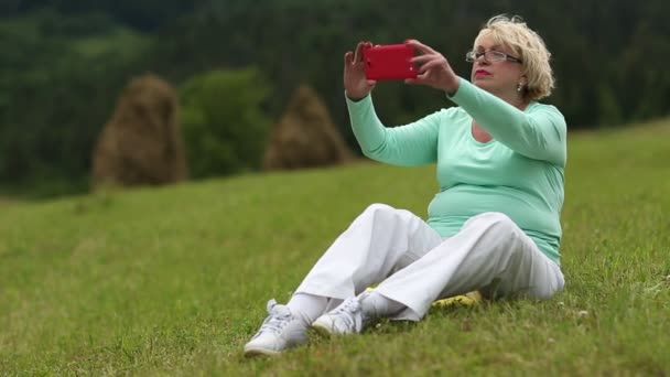 Блондинка робить фотографії на лузі — стокове відео
